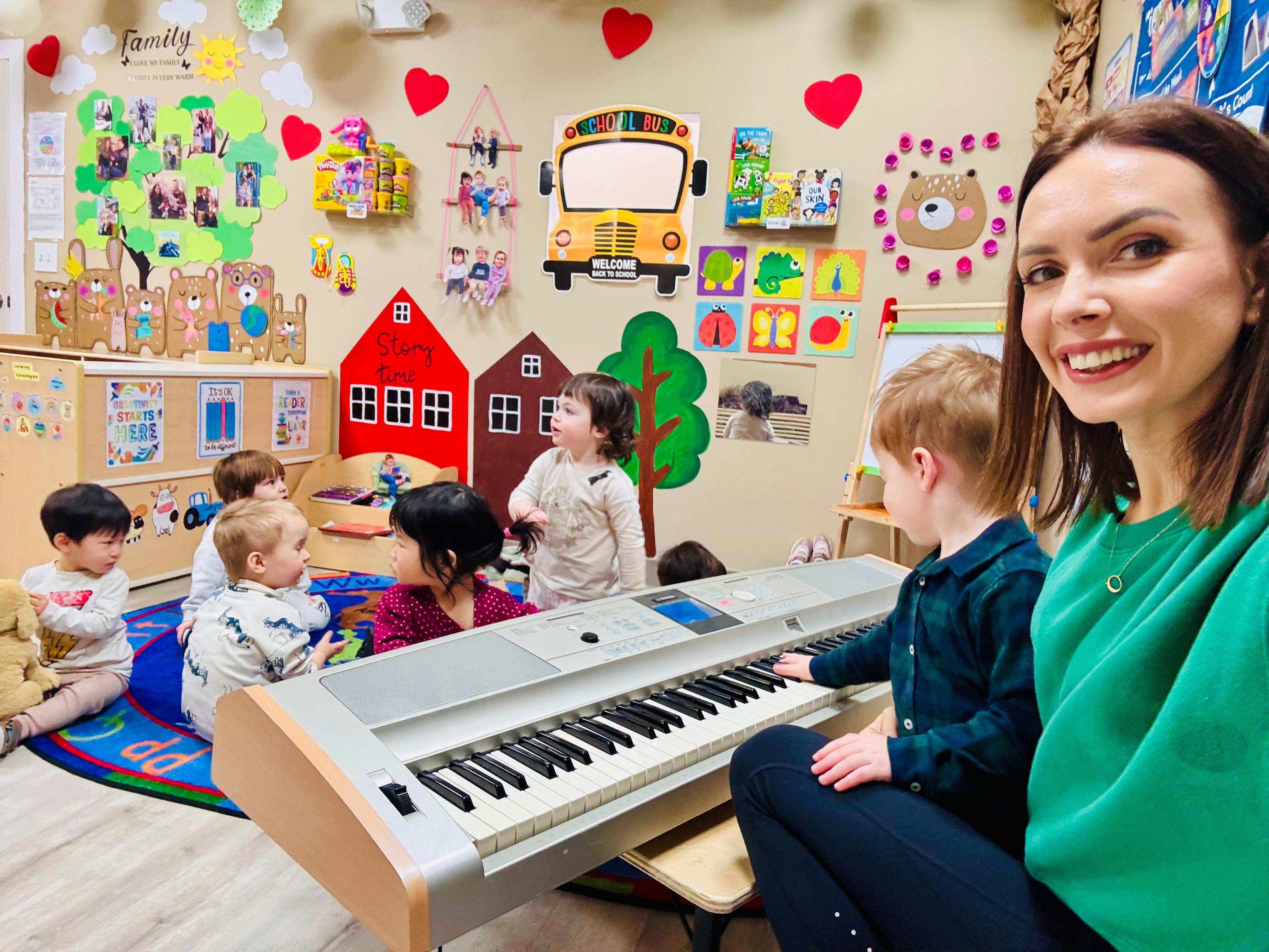 A music teacher and young child playing keyboard with classmates